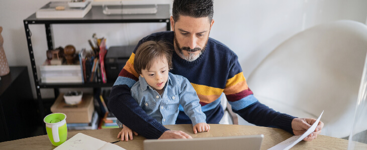 father with son sitting on his lap looking at computer with paper in his hands special needs planning